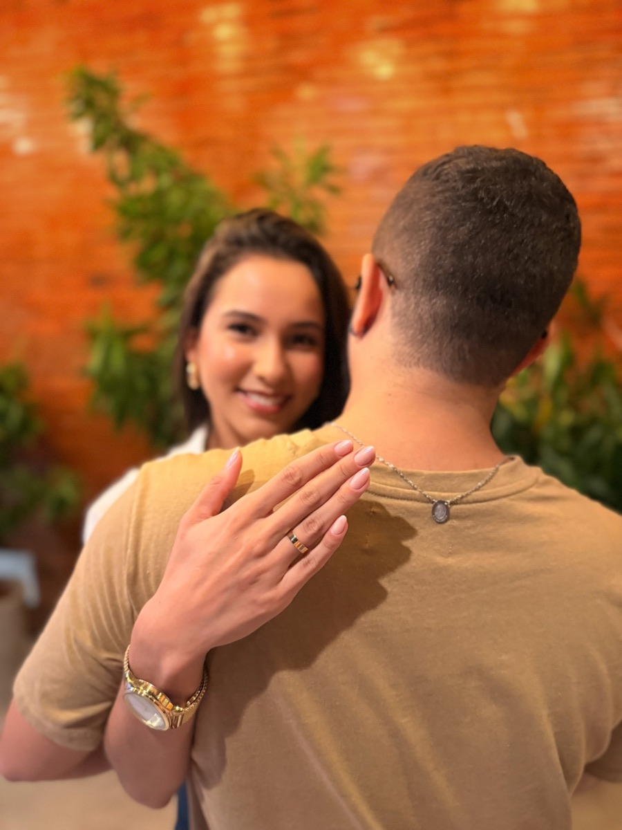 Tamires sorrindo por cima do ombro de Fernando, com a aliança na mão