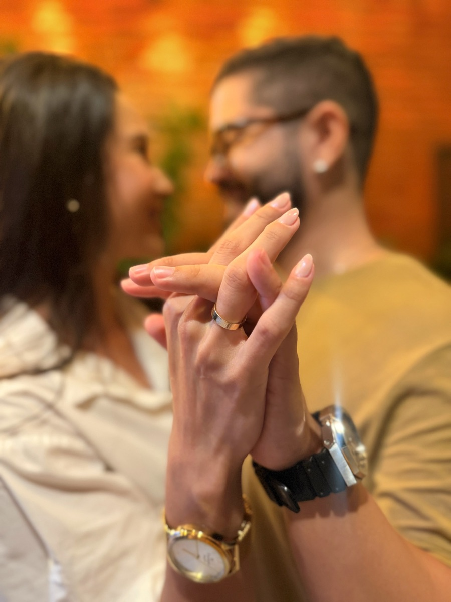 Mãos entrelaçadas do casal mostrando a aliança